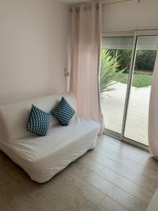biała kanapa z 2 niebieskimi poduszkami w salonie w obiekcie Belle maison de vacance avec piscine w mieście Ménesplet