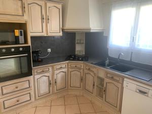 kuchnia z drewnianymi szafkami, umywalką i oknem w obiekcie Belle maison de vacance avec piscine w mieście Ménesplet +12 zdjęć