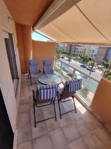 a balcony with chairs and a table and a view of a city at Apartamento Ático Laguna Beach Almerimar in Almería