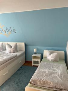 a bedroom with two beds and a blue wall at Ferienhaus Feldblick in Greifswald