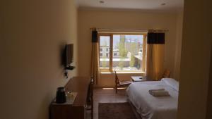 une chambre d'hôtel avec un lit et une fenêtre dans l'établissement 16 ARAHAT GUEST HOUSE, à Leh