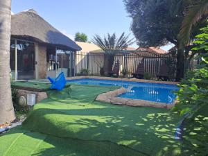 a yard with a putting green and a pool at Residential Inn in Pretoria