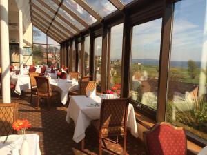 a restaurant with white tables and chairs and windows at Old Manor Hotel in Lundin Links