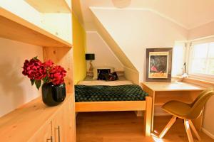 1 dormitorio con 1 cama, escritorio y un jarrón de flores en Loft am Malerweg, en Reinhardtsdorf