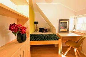 a bedroom with a bed and a desk and a vase of flowers at Loft am Malerweg in Reinhardtsdorf