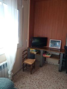 ein Schreibtisch mit einem Fernseher und einem Stuhl in einem Zimmer in der Unterkunft Apartamento-Casa turística l'Espígol in San Lorenzo de Morunys
