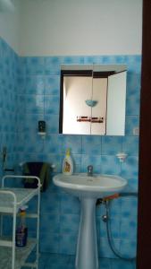 a blue tiled bathroom with a sink and a mirror at Villetta Mira in Torre Lapillo