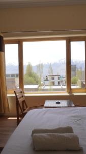 a bedroom with a bed and a large window at 16 ARAHAT GUEST HOUSE in Leh