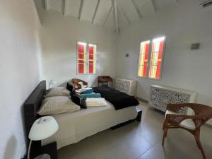 东方湾Villa SUNLIGHT Baie Orientale的一间卧室，里面有一张床、一把椅子和几扇窗户。