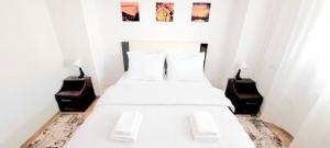 um quarto com uma cama branca com duas mesas de cabeceira em Brancoveanu Apartament's em Bucareste
