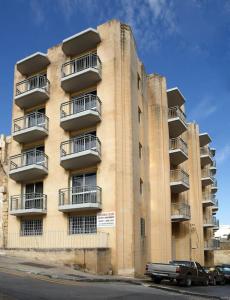 a tall building with balconies and a truck parked in front of it at 2 Bedrm Apt Seaview Balluta Bay (6) in Sliema