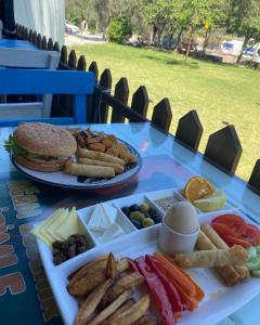 a table with a plate of food and a hamburger at Bodrum Masali Camping in Muğla