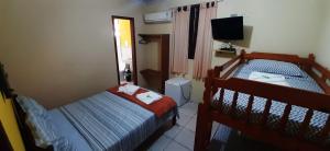a bedroom with two beds and a television in it at POUSADA PILLAR in Paraty