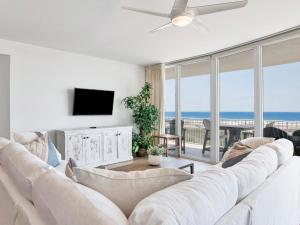 ein Wohnzimmer mit einem großen weißen Sofa und einem TV in der Unterkunft Caribe The Resort #C813 in Orange Beach