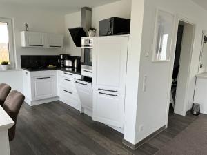 a white kitchen with white cabinets and a microwave at Ferienhaus Hilde 100m Entfernung zum See/Strand in Löbnitz