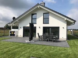 a white house with black chairs and a patio at Ferienhaus Hilde 100m Entfernung zum See/Strand in Löbnitz