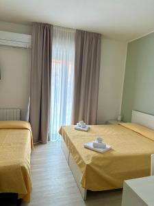 a hotel room with two beds and a window at Hotel La Bussola in Finale Ligure