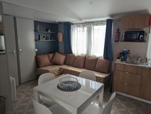 a living room with a couch and a table and chairs at En bord d'eau - charmant Mobil-home climatisé - Cap ferret in Lège-Cap-Ferret