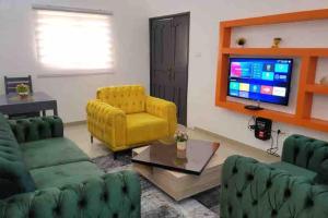 ein Wohnzimmer mit einem gelben Sofa und einem TV in der Unterkunft Résidence chez Jeanne in Agonkamè