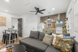a living room with a gray couch and a kitchen at NEW! The Yellow Door- Downtown Wimberley w/ River Access in Wimberley