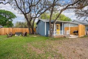 a blue house with a fence in a yard at NEW! The Yellow Door- Downtown Wimberley w/ River Access in Wimberley