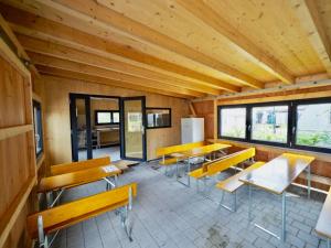 Habitación con mesas de madera, bancos y ventanas. en Holzhütte I26 groß en Reichenau