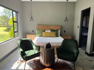 a bedroom with a bed and two green chairs at Swan Lake Suites in Benoni