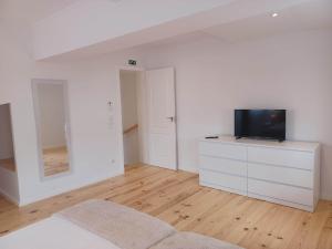 a white bedroom with a television on a dresser at Flor da Laranjeira in Elvas