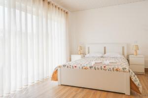 a white bedroom with a bed and white curtains at Casa Vilar R/C in Ponte de Lima