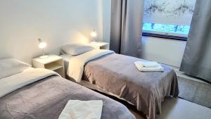 2 camas en una habitación con ventana y 2 lámparas en Aparthotel Clock 19 en Kotka