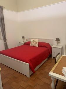 a bedroom with a bed with a red blanket and two tables at Relais Le Ortensie in Pisa