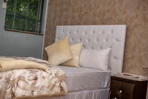 uma cama com uma cabeceira branca e almofadas em 66 Anglers Rod Guesthouse em Richards Bay