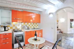 una cucina con armadi arancioni e un tavolo con una bottiglia di vino di Villa Volpe by DomusAway a Monte Petrosu