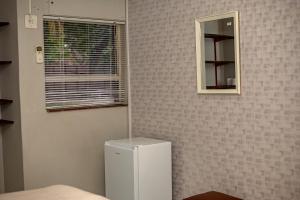 a small white refrigerator in a room with a mirror at 66 Anglers Rod Guesthouse in Richards Bay