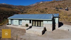 una pequeña casa con techo azul en una colina en Piri Home Casa de Montaña en Los Molles