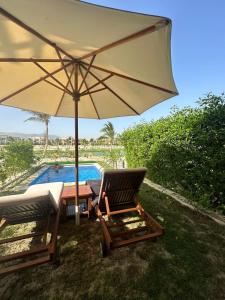 Ma‘mūrah的住宿－Hawana Salalah luxury 1BR TH with private pool，游泳池旁的两把椅子和一把遮阳伞