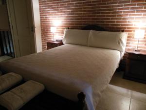 a bedroom with a white bed with a brick wall at Cabañas Valeria Kaupe in Valeria del Mar