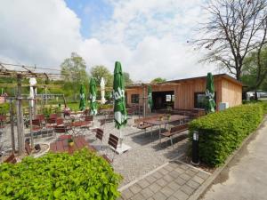 un patio con mesas, sombrillas verdes y bancos en Holzhütte J24 Klein en Reichenau
