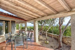a patio with a table and chairs under a wooden ceiling at Volpe by DomusAway in Monte Petrosu