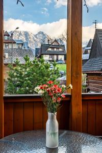 un jarrón con flores sentado en una mesa frente a una ventana en Willa Ela Cri en Zakopane