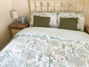 a bed with a floral bedspread and pillows on it at Whitney Cottage in Broadway