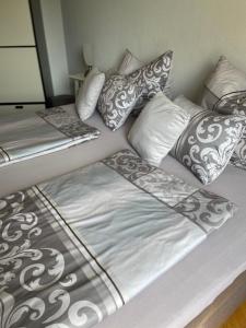 łóżko z białymi i szarymi poduszkami w obiekcie Cityapartment direkt am Hafen w mieście Friedrichshafen