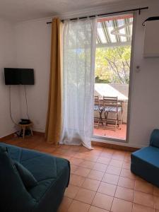 salon z kanapą i przesuwnymi szklanymi drzwiami w obiekcie Studio Mer et Vacances w mieście Sausset-les-Pins