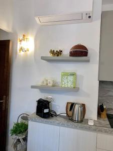 une cuisine avec des murs et des étagères blancs et un comptoir dans l'établissement Buganvillea Cottage: un nido a 200 mt. dal mare, à Porto Pollo