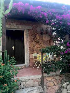 - un bâtiment en pierre avec une porte ornée de fleurs violettes dans l'établissement Buganvillea Cottage: un nido a 200 mt. dal mare, à Porto Pollo