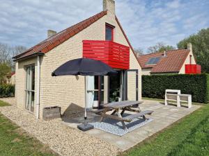 a picnic table and an umbrella in front of a house at Lakeview 'Rotorua' 4-6 pers by Kawatea Cottages in Ewijk