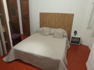 1 dormitorio con cama blanca y cabecero de madera en Casa Padulella (4 appartements), en Moriani Plage
