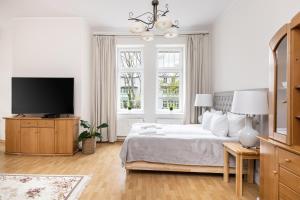 a white bedroom with a bed and a flat screen tv at Apartamenty Vincent Sopot in Sopot