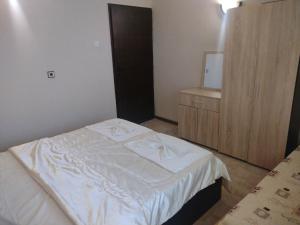 1 dormitorio con cama blanca y armario de madera en Prostor Guest House, en Byala