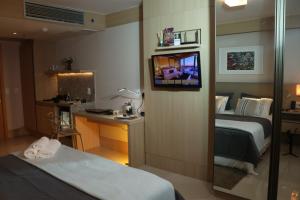 a hotel room with a bed and a desk and a mirror at Flat Premium Particular Cullinan Hotel in Brasília